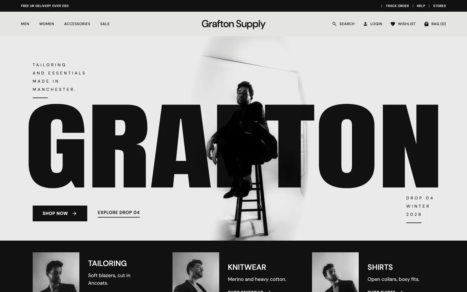 Grafton Supply homepage: GRAFTON in huge black condensed letters with a model in a black suit sitting on a stool in front of it, in a black and white studio, over a black strip of tailoring, knitwear and shirts.