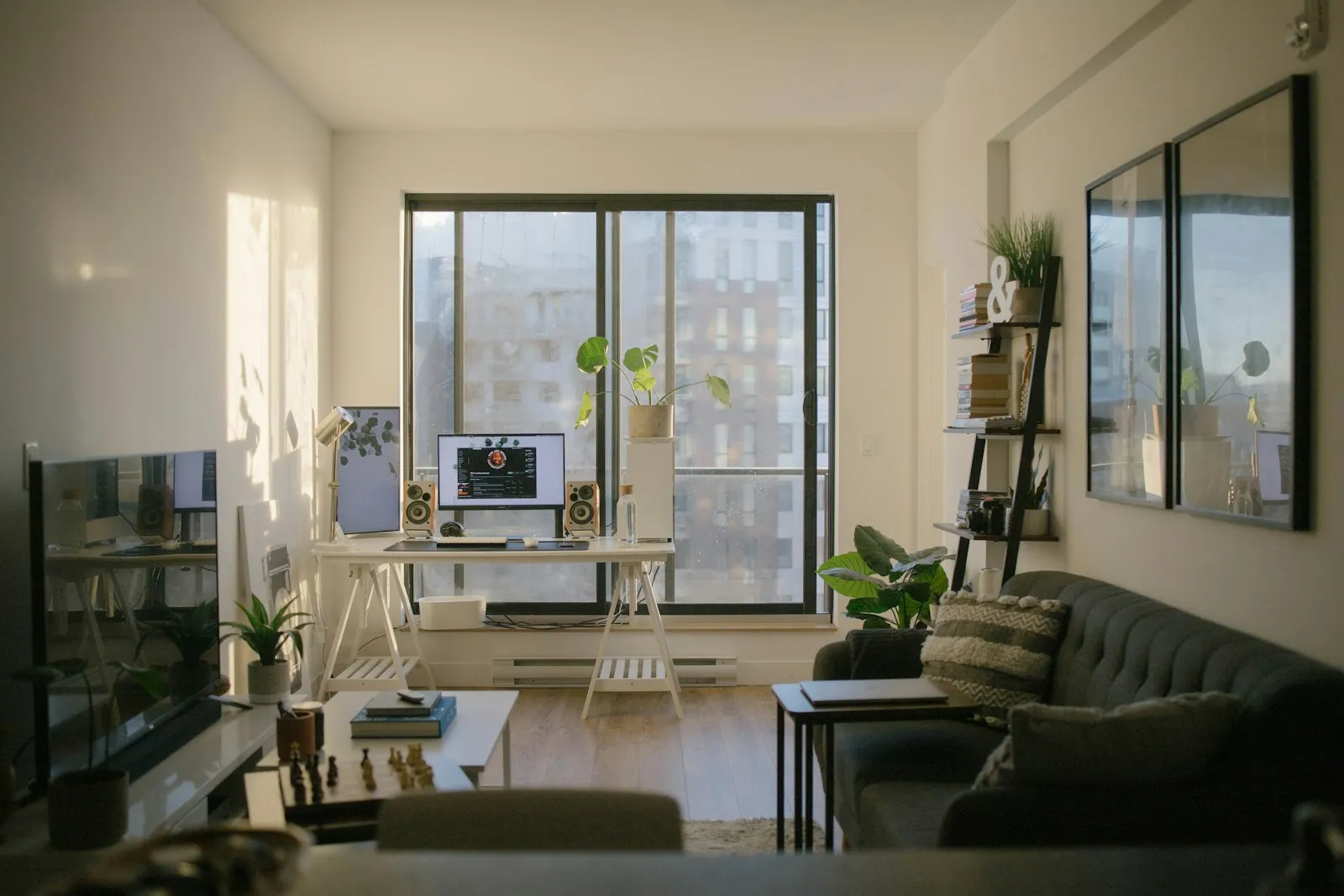 An open-plan apartment with a dining table and tall windows over the city.